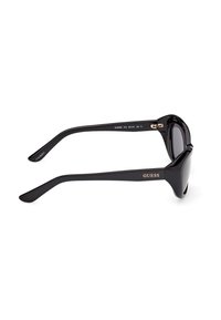 Lunettes de soleil Guess noires avec des montures épaisses et des verres teintés, vues de profil avec le logo de la marque visible sur la branche.