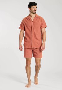 Kurzärmliges, lässig geschnittenes Hemd und passende Shorts aus koralfarbener, strukturierter Stoffqualität mit Brusttasche und Knopfverschluss.