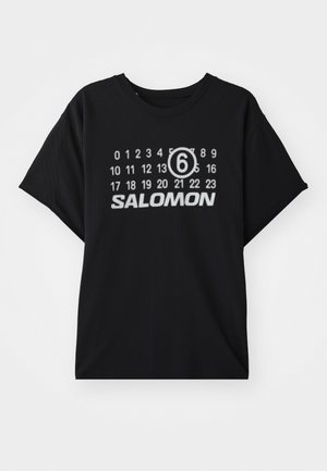 Svart T-skjorte med korte ermer, med et hvitt grafikkmotiv av tall og "SALOMON"-tekst på fronten. Myk tekstur og avslappet passform.
