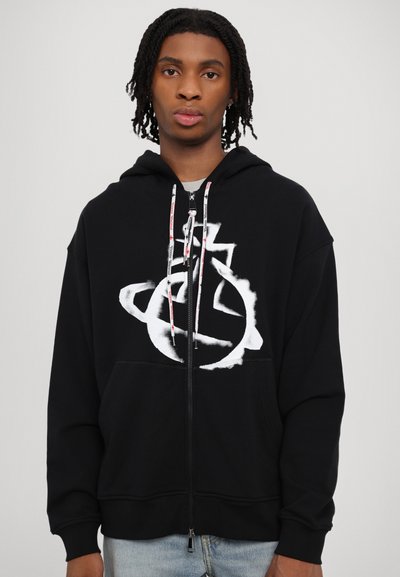 Black zip-up hoodie with a large white graphic design on the front, featuring drawstrings with red accents and a relaxed fit.