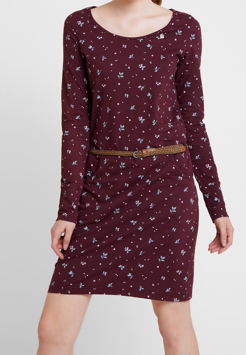 Langärmliges, kastanienbraunes Kleid mit kleinen Blumenmustern. Verfügt über einen runden Halsausschnitt und einen geflochtenen braunen Gürtel in der Taille.