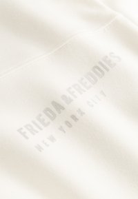 Beige Sweatshirt mit weichem Material und einem kleinen, grauen Logo-Druck, das "FRIEDA & FREDDIES NEW YORK CITY" zeigt.
