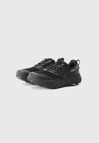 Black trail running shoes with mesh and synthetic upper, textured outsole, prominent toe cap, and Vibram logo on the side.