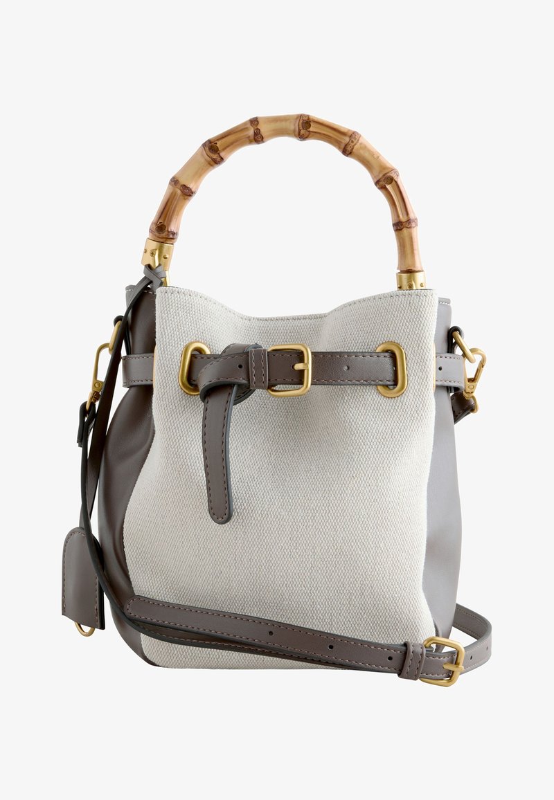 Sac à main en toile et cuir avec poignée en bambou, bandoulière en cuir réglable et détails de boucle et ferrures dorés.