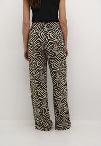Pantalon en imprimé zèbre beige et noir, avec une coupe ample, une taille élastique et un tissu léger pour le confort.