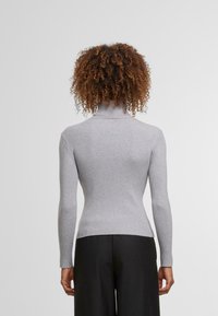 Szary, prążkowany sweter z golfem, z długimi rękawami, dopasowany krój i gładka textura. Widok z tyłu ukazuje gładkie wykończenie i brak widocznych detali.