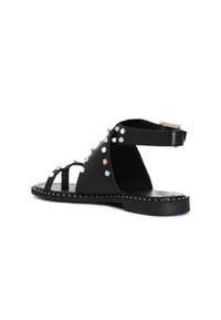 Sandale negre din piele, cu studuri decorative în albastru, roz și alb, având curea pentru glezne și talpă plată cu margine rotunjită.