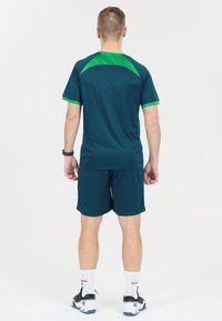 Herrarnas idrottskläder i teal med gröna accenter. Den kortärmade toppen har en rund halsringning och shortsen är i enfärgad teal.