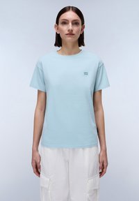 Lichtblauw katoenen t-shirt met korte mouwen en een ronde hals. Heeft een klein logo in de linkerbovenhoek. Zorgt voor een soepele textuur.