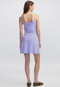 Lilac gebreide twee-delige set met een mouwloze crop top en een uitlopende rok, beide met een gestructureerde afwerking. Geaccentueerd met zwart en bruin panterprint schoenen.