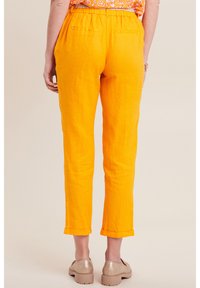 Helle orange Leinenhosen mit lockerem Sitz, elastischem Bund und umgeschlagenen Bündchen. Verfügt über zwei Gesäßtaschen und eine strukturierte Oberfläche.