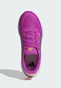Chaussure de sport violette avec tige en maille, design à lacets et trois bandes argentées. Caractéristiques des accents oranges sur la languette et une semelle rembourrée.
