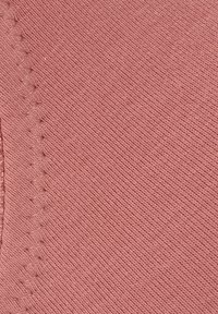 Weicher, strukturierter Baumwollstoff in einem gedämpften Rosa mit sichtbarem Rippenmuster und einer dekorativen gestickten Kante.