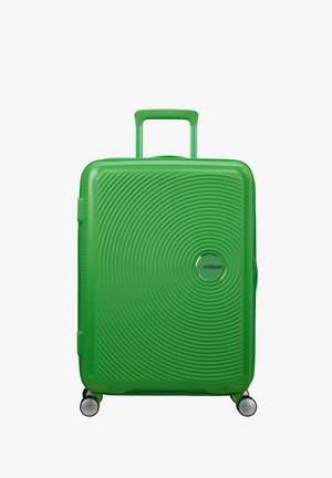 Green hard-shell suitcase with a textured wave pattern, extendable handle, and four spinner wheels for mobility. Features a logo detail.