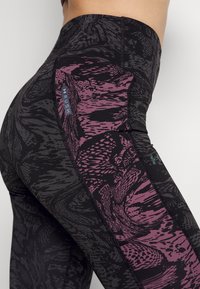 Hochtaillierte Leggings in Schwarz mit einem strukturierten Muster in Lila. Mit einer seitlichen Tasche und einem Logo-Tag. Dehnbares Material für mehr Komfort.