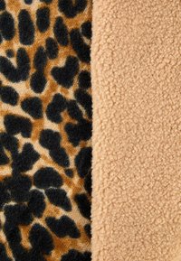 Leopard print fabric in brown and black alongside a soft, textured beige fleece. Distinct patterns and cozy surface qualities visible.