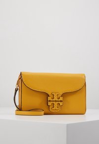 Bolso bandolera de cuero amarillo con un acabado texturizado, que presenta un cierre con solapa, herrajes en tono dorado y un distintivo acento de logo.