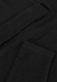 Schwarzer Stoff mit einer strukturierten Oberfläche, der glatte Kanten und ein gefaltetes Design aufweist. Das Material erscheint weich und leicht.