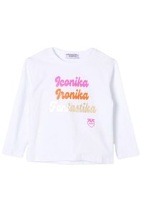 Camicia bianca a maniche lunghe con le parole "Iconika", "Ironika" e "Fantastika" in testo metallico rosa, arancione e oro.