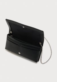 Bolso de mano negro con textura, solapa abierta que muestra un compartimento con cremallera y cadena plateada sobre fondo blanco.
