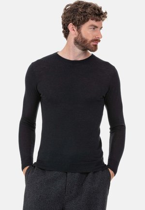 Schwarzes Langarmshirt mit Rundhalsausschnitt in figurbetontem Design, aus leichtem Stoff mit glatter Textur, kombiniert mit grauer, strukturierter Hose.