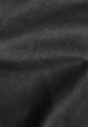 Tessuto nero con una consistenza liscia e opaca, caratterizzato da un motivo sottile. Il materiale appare resistente, con leggere pieghe che indicano flessibilità.