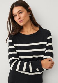 Gestreept sweater in zwart en wit, gemaakt van een zachte breimateriaal. Heeft een ronde halslijn en ribbelmanchetten met een relaxte pasvorm.