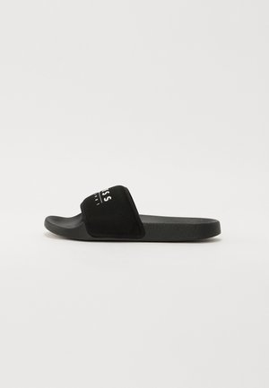 Black slide sandal with a textured rubber sole. Features a wide mesh strap with white logo detailing across the top.