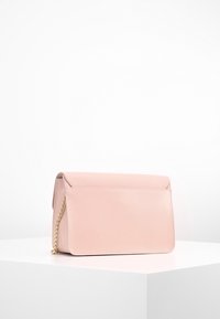 Růžová texturovaná kožená kabelka se zavíráním na klopu a zlatým řetězovým popruhem, s minimalistickým obdélníkovým tvarem a hladkým povrchem.