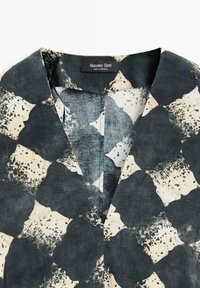Schwarz-weiß abstrakt gemusterter Hemdkragen mit einem "Massimo Dutti Made in Morocco" Etikett.