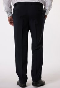 Marinefarbene Anzughose mit schmaler Passform, ausgestattet mit zwei Gesäßtaschen, scharfen Bügeln und einer glatten Textur, kombiniert mit schwarzen Schuhen.