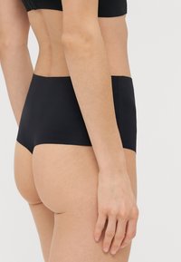 Fekete, magas derekú bugyi sima anyagból készült, zökkenőmentes kialakítással és minimalista stílussal, látható hardver vagy kiegészítők nélkül.