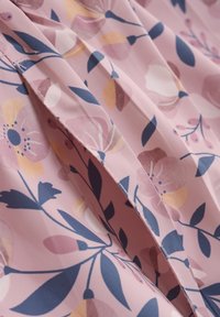Blomstermønstrede stof i lys pink med marineblå, orange og creme nuancer. Polyester materiale med en glat tekstur og plisseret design.