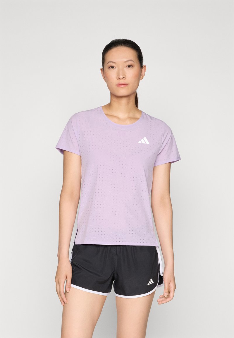 Lichtpaarse sportt-shirt met korte mouwen, voorzien van een gestippeld textuur en een wit logo. Draagt met een zwarte short, geaccentueerd met witte rand.