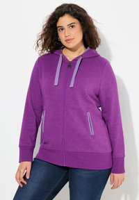 Felpa con zip viola e cappuccio regolabile con cordino, due tasche laterali e dettagli grigi a contrasto. Tessuto morbido e vestibilità comoda.