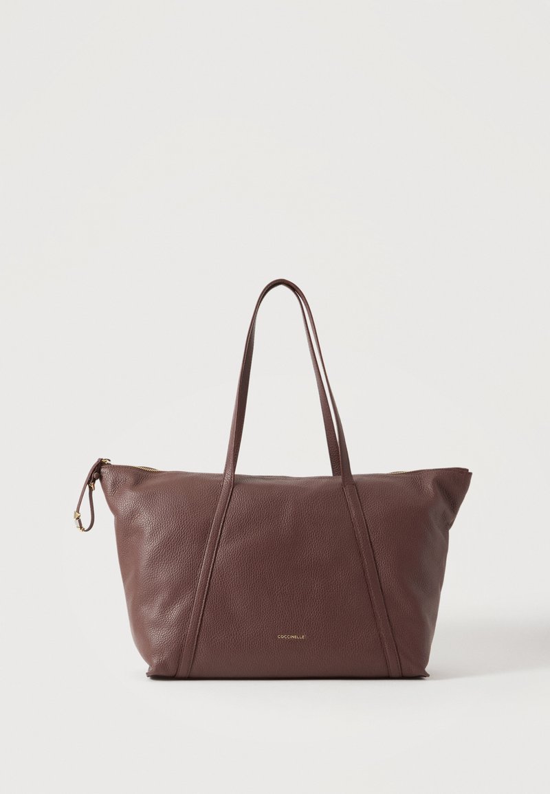 Sac cabas en cuir marron avec double bandoulière, fermeture éclair sur le dessus et petit logo doré de la marque sur le devant.
