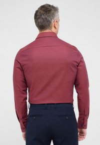 Bordeaux langemouwen shirt met een gestructureerd patroon, knoopmanchetten en een klassieke kraag, gecombineerd met donkerblauwe broeken.