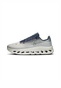 Leichter Laufschuh in Grau und Marineblau. Mit atmungsaktivem Mesh-Obermaterial, dicker weißer Sohle mit Ausschnitten und flachen blauen Schnürsenkeln.