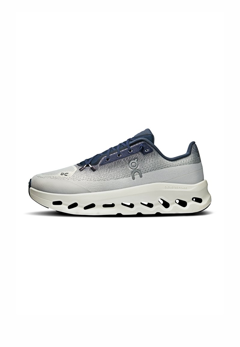 Leichter Laufschuh in Grau und Marineblau. Mit atmungsaktivem Mesh-Obermaterial, dicker weißer Sohle mit Ausschnitten und flachen blauen Schnürsenkeln.