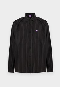 Μαύρο πουκάμισο με μακριά μανίκια και κουμπιά, με λεπτές κατακόρυφες λευκές ρίγες, δύο τσέπες στο στήθος και μια μικρή μωβ ετικέτα λογότυπου στην αριστερή τσέπη.
