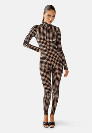 Rekbare zwart-beige houndstooth geblokte bodysuit met lange mouwen en hoge hals, gecombineerd met zwarte peep-toe hakken.