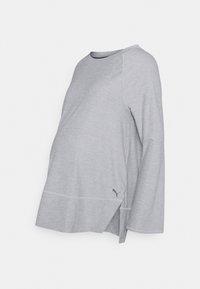 Šedé těhotenské tričko s dlouhým rukávem, kulatým výstřihem, raglánovými rukávy, bočním rozparkem a malým logem na spodním okraji. Vyrobeno z měkké látky.