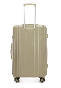 Valigia rigida di colore beige chiaro, con superficie testurizzata, scanalature verticali, doppie ruote e manico retrattile.