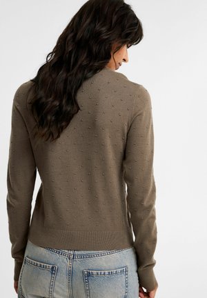 Brun tekstureret sweater med hævede prikmønstre, ribbet kant og manchetter, rund halsudskæring og en tætsiddende silhuet. Vist bagfra.