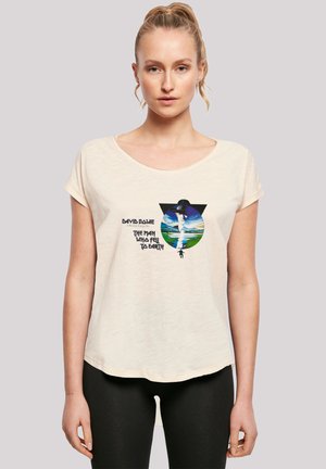 Beige, short-sleeved t-shirt with a round neckline featuring a printed graphic of a figure and landscapes, labeled "David Bowie: The Man Who Fell to Earth."