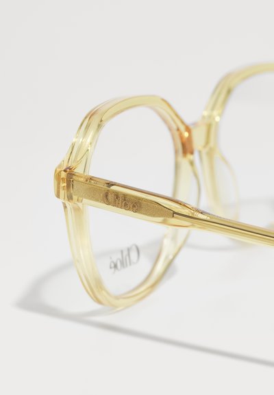 Occhiali da vista in acetato giallo trasparente con montatura rettangolare, dotati di un'asta in metallo piatto incisa con "Chloé" e superfici lisce.