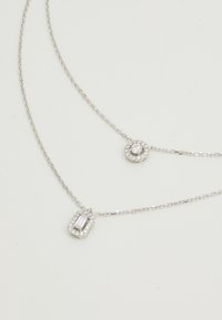 Collana d'argento con due pendenti: uno rettangolare con taglio smeraldo e uno circolare. Entrambi presentano piccole gemme incastonate.