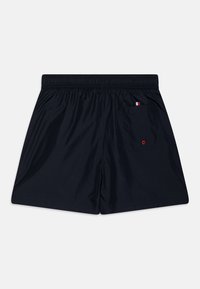 Námořnické modré plavky s elastickým pasem, které mají zadní kapsu a malý červený, bílý a modrý akcent na kapse.