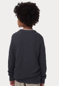 Maglione a maglia grigio scuro con un motivo testurizzato, maniche raglan e polsini e orlo a costine. La vista posteriore mostra il colletto arrotondato.