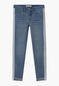 Pantalones vaqueros ajustados en denim azul medio con franjas laterales plateadas, con un diseño clásico de cinco bolsillos y dobladillo deshilachado en la parte inferior.